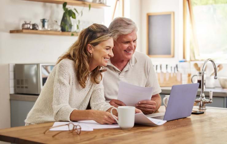 Older couple on their laptop checking their finances in their kitchen