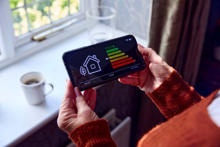 Woman holding a smart meter in her hands on her smartphone
